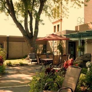 A peaceful backyard patio with outdoor seating and a garden, basking in sunny weather.