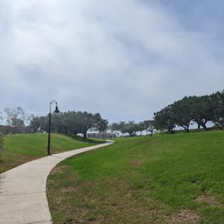 A winding pathway through a lush green park under a cloudy sky.