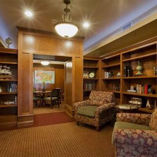 A cozy library reading room with comfortable armchairs and wooden bookshelves.