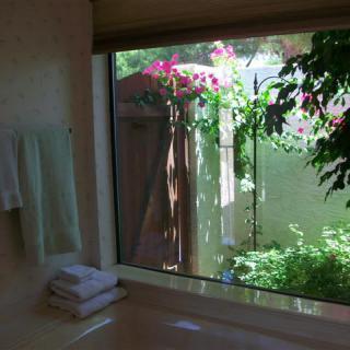 A serene bathroom with a large window offering a view of lush greenery and vibrant flowers outside.