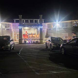 A brightly lit hotel entrance at night, surrounded by parked cars.