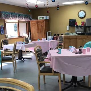 A dining area with tables covered in pink tablecloths and chairs arranged around them.