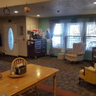 Cozy living room with a dining table and chairs, featuring large windows and comfortable seating.