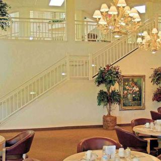 A spacious dining area with elegant chandeliers and a grand staircase.