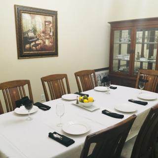 A formal dining room setup with a white tablecloth, neatly arranged plates, and black napkins.