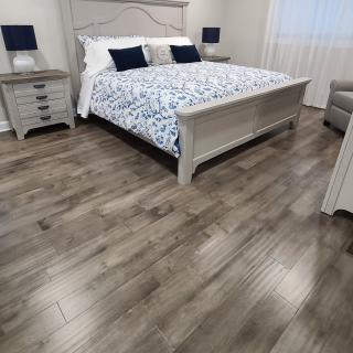 A modern bedroom featuring a large bed with patterned bedding, nightstands with lamps, and hardwood flooring.