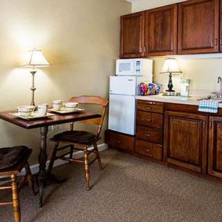 A cozy kitchen and dining area with wooden cabinets, a small table with chairs, and soft lighting from table lamps.