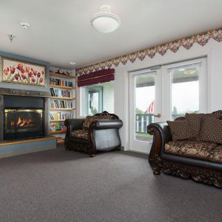 A cozy living room featuring a fireplace, elegant sofas, and a bookshelf.
