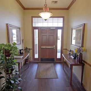 An inviting hallway with a wooden door, decorated with plants and mirrors on side tables.