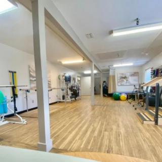 A spacious indoor gym with exercise equipment and wooden flooring.