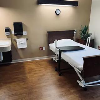 A clean and well-organized hospital patient room with a single bed and sink.
