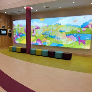 A vibrant and playful waiting area designed for children, featuring a large colorful mural and cozy seating.