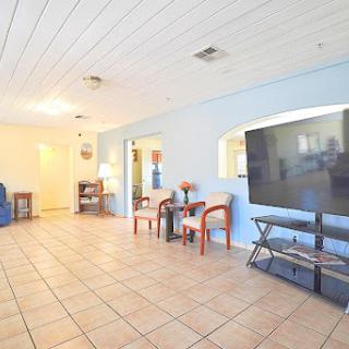 A spacious living room featuring blue walls and tiled flooring, equipped with modern furniture and a large television.