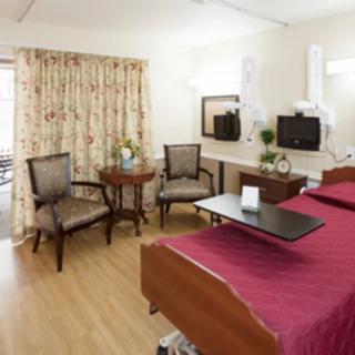 A well-furnished hospital room with a bed and seating area.