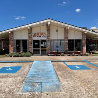 A storefront with handicap accessible parking in a clear blue sky.