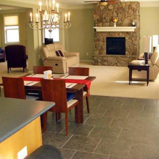An open-concept living and dining area featuring a stone fireplace, a chandelier, and modern furniture.
