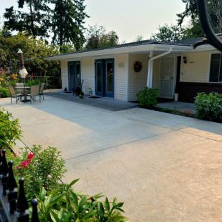 A quaint house with a driveway and a garden patio surrounded by plants.