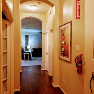 A cozy hallway with wooden flooring, decorated with artwork and equipped with a fire extinguisher.