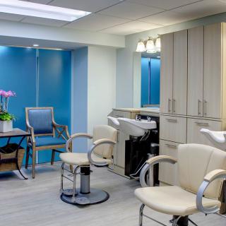 A modern salon interior with stylish chairs and hair washing stations against a backdrop of blue walls.