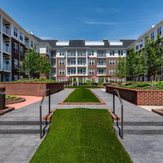 A modern apartment complex featuring a landscaped courtyard with pathways and green spaces.