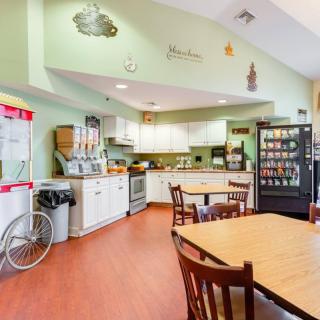 A cozy dining and kitchen area with tables and chairs, featuring a vending machine and coffee station.