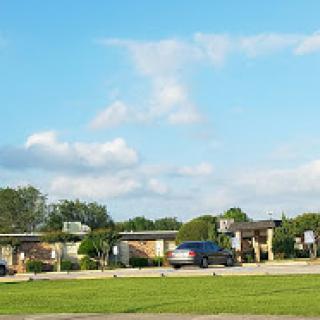 A view of residential buildings under a bright sky with scattered clouds.