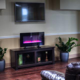 A cozy living room setup featuring a wall-mounted television and a stylish TV stand with an electric fireplace.