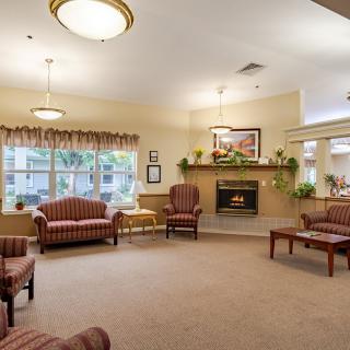 A cozy living room with sofas and a fireplace, featuring warm lighting and elegant decor.