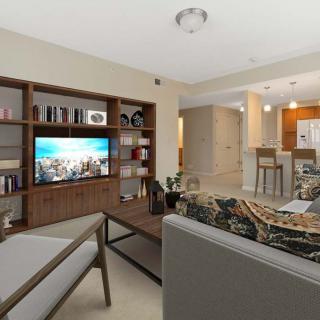 A modern living room with comfortable seating, a large TV, and an open view into the kitchen area.