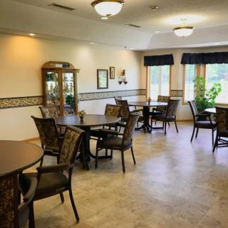A well-lit dining area with multiple tables and chairs, featuring decorative elements and large windows.
