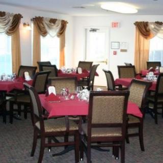 A dining room with tables set with red tablecloths and neatly arranged chairs.