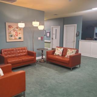 A cozy living room with orange sofas, a standing lamp, and artwork on the wall.