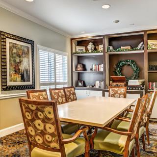 A well-organized conference room with a large table, floral-patterned chairs, and decorated bookshelves.