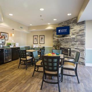 A cozy dining area with tables and chairs, featuring a television mounted on a stone wall.