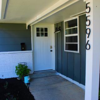 A modern house entrance featuring a white door with adjacent windows, displaying the number 5596 on the wall.