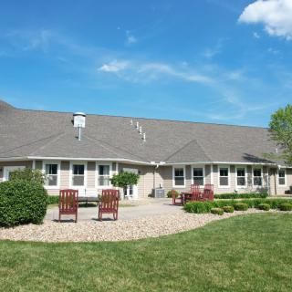 A suburban house with a spacious patio and well-maintained garden under a clear blue sky.