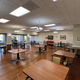A spacious dining area with well-arranged tables and chairs, featuring soft lighting.