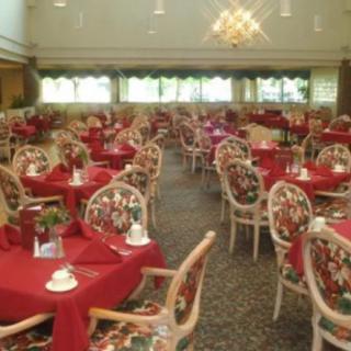 An elegant restaurant dining room with red tablecloths and floral patterned chairs.