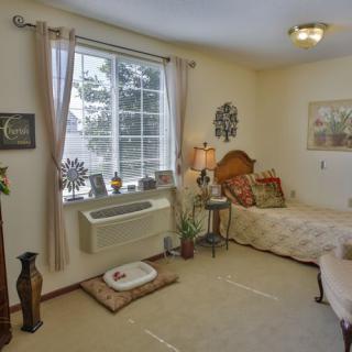 A cozy bedroom with a single bed, decorative elements, and natural light coming through the window.