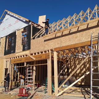 Construction site showing workers assembling the wooden framework for a roof.