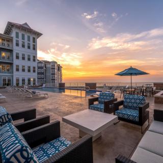 A luxurious resort with outdoor seating overlooking a stunning sunset by the pool.