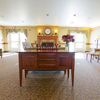 A warmly lit lobby with a central wooden table adorned with flowers and decorative items.
