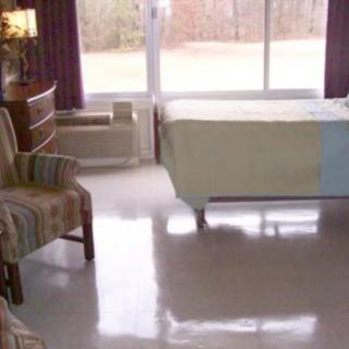 A simple room with a bed, chair, and large window.
