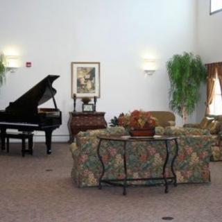 A spacious living room with a grand piano and floral sofas.