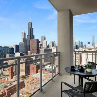 A stunning cityscape view from a modern balcony featuring outdoor seating.