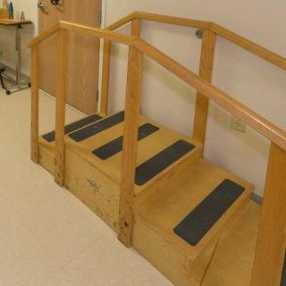Wooden indoor stairs with handrails, possibly used for exercise or rehabilitation.
