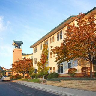 A college building with a clock tower surrounded by autumn foliage.