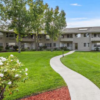 A well-maintained apartment complex with a landscaped lawn and a winding pathway.