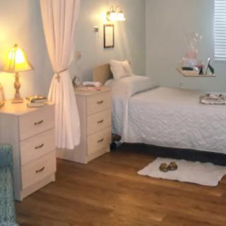 A cozy bedroom with a single bed, nightstand, and soft lighting.
