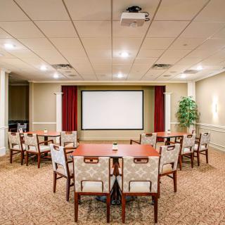 A well-organized conference room featuring a central projector and seating arranged around tables.